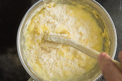 Brandteig herstellen, Schritt 2: Mehl auf einmal zugeben und unter das Butter-Milch-Gemisch rühren
