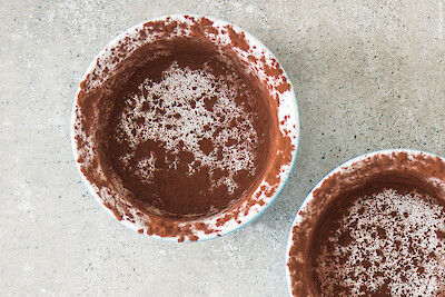 Zwei Förmchen, vorbereitet für Fondant au chocolat: mit Butter ausgestrichen und mit Kakao bestäubt