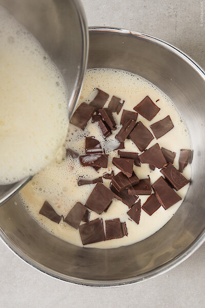 In Stücke gebrochene Schokolade in einer Sauteuse wird mit heißer Sahne übergossen