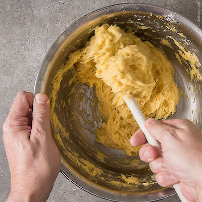 Aus geriebenen Kartoffeln, Eiern und Mehl wird Kartoffelpuffermasse in Edelstahlschüssel gerührt